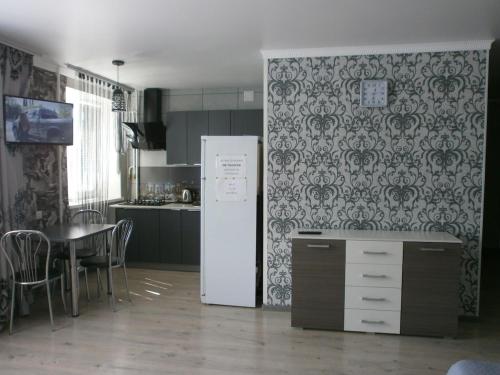 a kitchen with a refrigerator and a table with chairs at Однокімна квартира в центрі міста in Myrhorod