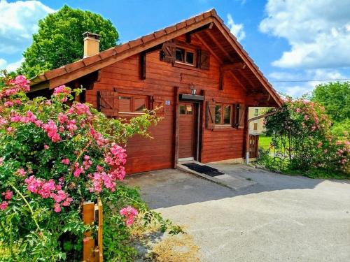 a wooden house with a garage and some flowers at Chalet Le Petit Prince in Saffloz