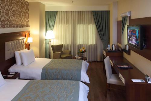 a hotel room with two beds and a desk at Hotel Senbayrak City in Adana