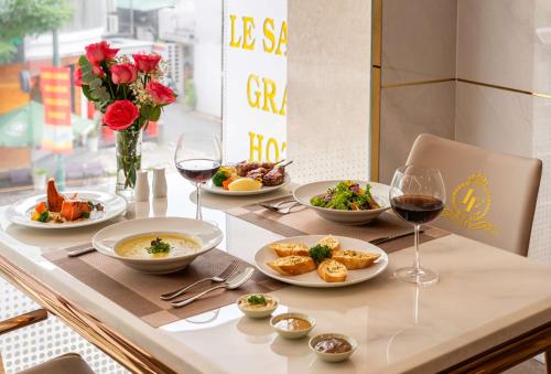 a table with plates of food and glasses of wine at Le Saigon Grand Hotel in Ho Chi Minh City