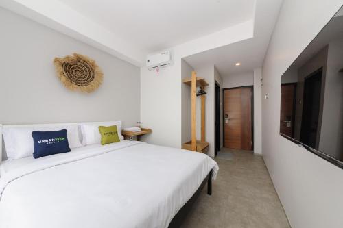 Un dormitorio blanco con una cama blanca y un televisor. en Urbanview Hotel Puri Indah, en Yakarta