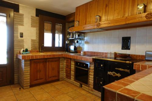 a kitchen with wooden cabinets and black appliances at Cal Fuse in Fonollosa