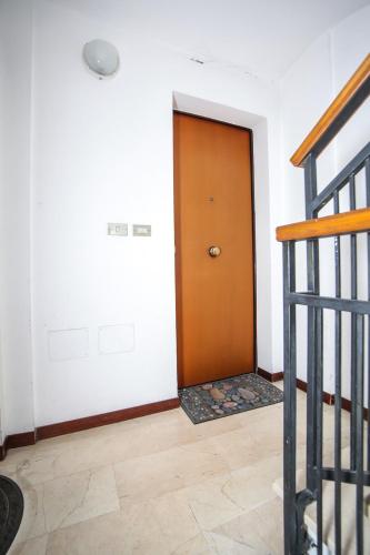 a brown door in a white room with a staircase at Guest House Formigine in Formigine