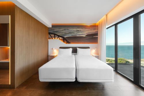 a bedroom with a large white bed with a view of the ocean at Eurostars Cascais in Cascais