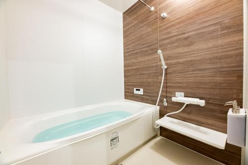 a bathroom with a tub and a wooden wall at Irodori Hotel HOTARU in Fukuoka