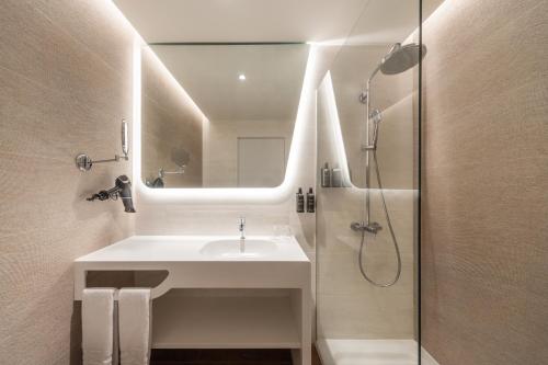 a bathroom with a sink and a shower with a mirror at Eurostars Cascais in Cascais