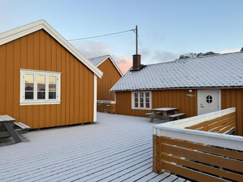 a deck with two buildings and a picnic table at Sakrisøy Rorbuer in Reine