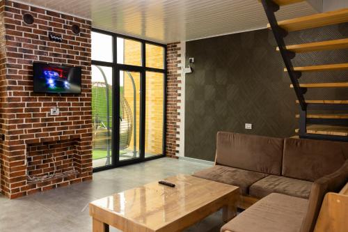 a living room with a couch and a tv on a brick wall at Harmony Escape in İsmayıllı
