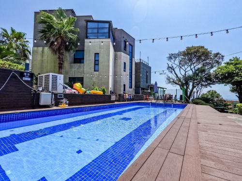 a swimming pool in front of a building at Monaco Pool Pension in Seogwipo