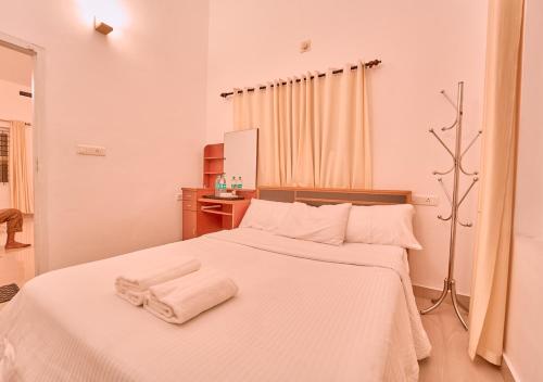 a bedroom with a white bed with towels on it at Kedara Resort Wayanad by VOYE HOMES in Sultan Bathery