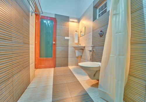 a bathroom with a toilet and a red door at Kedara Resort Wayanad by VOYE HOMES in Sultan Bathery
