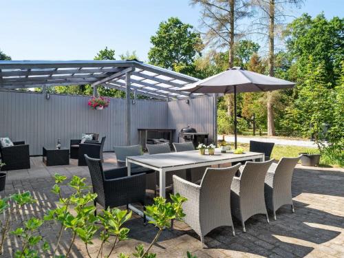 a patio with a table and chairs and an umbrella at Holiday Home Tannie - 300m from the sea by Interhome in Strøby