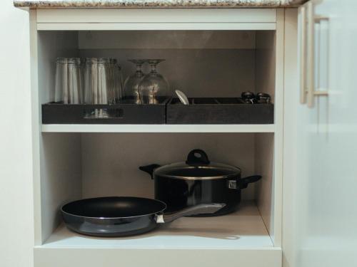 ein Schrank mit einem Topf und einer Pfanne auf einem Regal in der Unterkunft Hannah's Place in Davao City