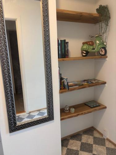 a mirror hanging on a wall next to a shelf at Lejlighed Østergade Herning in Herning