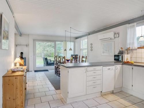 a kitchen with white cabinets and a dining room at Holiday Home Torhild - 150m from the sea by Interhome in Martofte