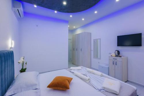a white bedroom with a bed with a television on the wall at Apart-Hotel President 2 in Ulcinj
