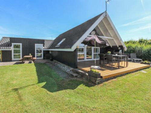 a house with a deck with a table and an umbrella at Holiday Home Elbert - 100m from the sea by Interhome in Otterup