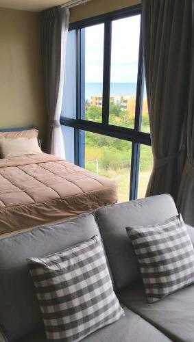 a bedroom with two beds and a large window at Baan Thew Talay Blue Sapphire in Cha Am