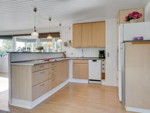 a kitchen with wooden cabinets and a white refrigerator at Holiday Home Ilene - 1km from the sea by Interhome in Bogø By