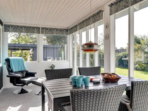 a screened in porch with a wooden table and chairs at Holiday Home Ilene - 1km from the sea by Interhome in Bogø By