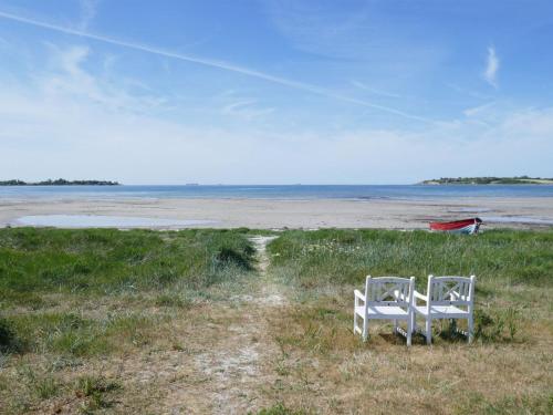 two white chairs sitting in the grass near the beach at Holiday Home Sazur - 75m from the sea by Interhome in Mesinge