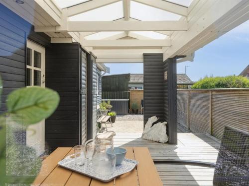 a patio with a wooden table and a white pergola at Holiday Home Sazur - 75m from the sea by Interhome in Mesinge