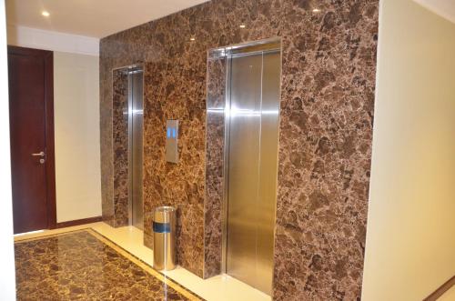 y baño con ducha de azulejos marrones. en Shada Residence Hotel en Al Khobar