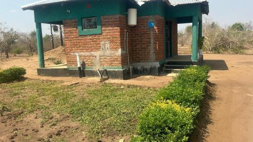 a small brick building with a green roof at Dewclaw Baobob Safari Lodge in Mfuwe
