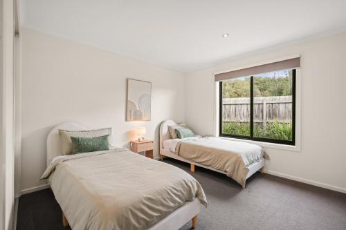 ein Schlafzimmer mit zwei Betten und einem Fenster in der Unterkunft Malabar Retreat by Ready Set Stay in Cowes