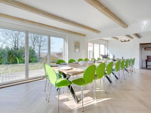a dining room with a long table and green chairs at Holiday Home Rouwen - 1km from the sea by Interhome in Sakskøbing