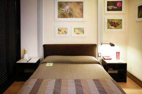 a bedroom with a bed with two tables and pictures on the wall at Art Hotel Museo in Prato