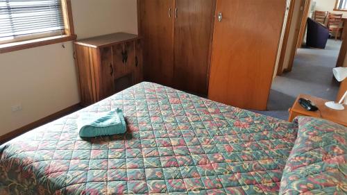 a bedroom with a bed with a green comforter at Waratah Falls Holiday Unit in Waratah