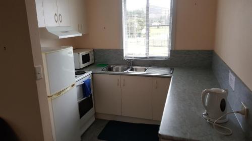 a small kitchen with a sink and a refrigerator at Waratah Falls Holiday Unit in Waratah