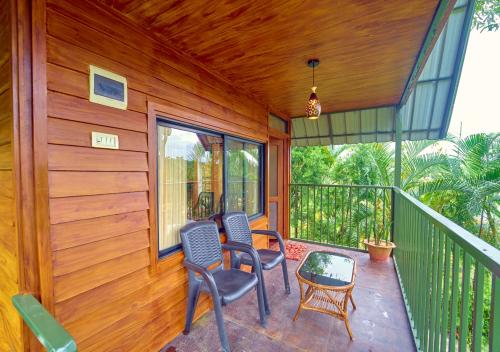a porch of a house with two chairs and a table at Kedara Resort Wayanad by VOYE HOMES in Sultan Bathery