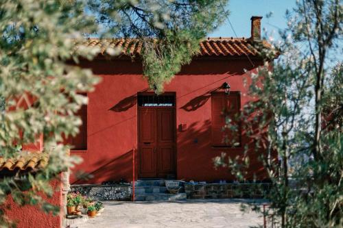 a red house with a red door and trees at Δωμάτια Κόκκινος Πύργος in Plomarion