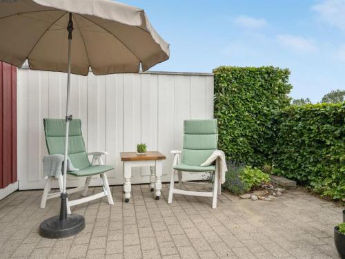 two chairs and an umbrella on a patio at Holiday Home Eike - 250m from the sea by Interhome in Bro