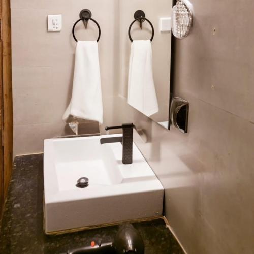 a bathroom with a white sink and a mirror at Onyx Hotel & Resort, Jim Corbett in Jāmb