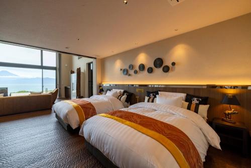 two beds in a hotel room with a large window at 富士青藍 in Numazu
