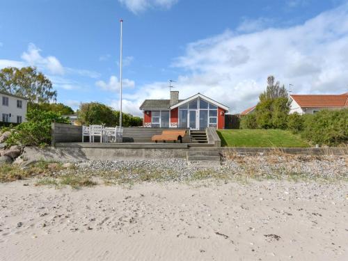 a red and white house with a bench on the beach at Holiday Home Keti - 5m from the sea by Interhome in Nyborg