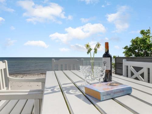 a bottle of wine and a book on a table on the beach at Holiday Home Keti - 5m from the sea by Interhome in Nyborg