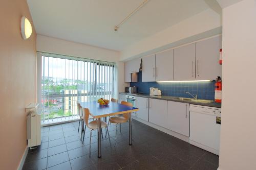 a kitchen with white cabinets and a table with chairs at Victoria Mills Apartments - UCC Summer Beds in Cork