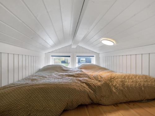 a large bed in a white room with a ceiling at Holiday Home Antti - 350m from the sea by Interhome in Millinge