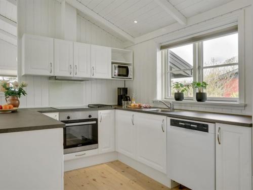 a white kitchen with white cabinets and a window at Holiday Home Antti - 350m from the sea by Interhome in Millinge