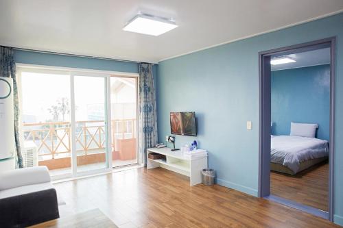 a bedroom with blue walls and a bed and a window at 제주토비스콘도 신관 in Kwakchi-ri