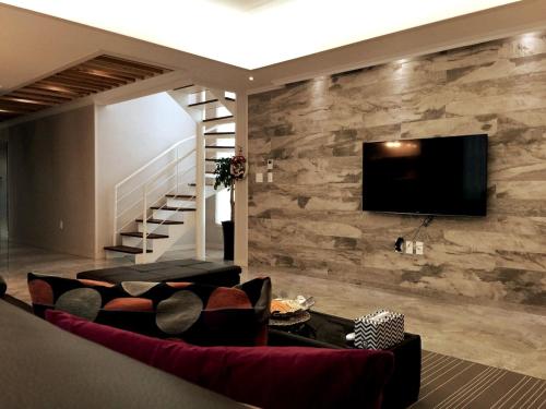 a living room with a tv on a stone wall at Oh Happy Day Jeju in Jeju