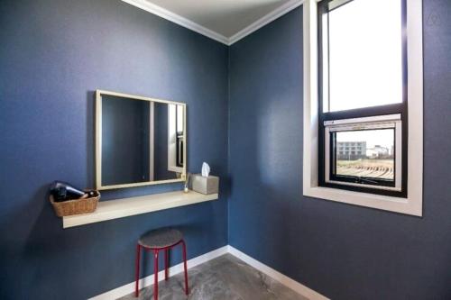a blue room with a mirror and a stool at Oh Happy Day Jeju in Jeju