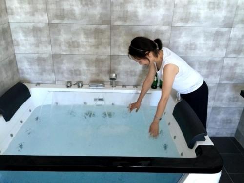 a woman standing in a tub in a bathroom at Oh Happy Day Jeju in Jeju