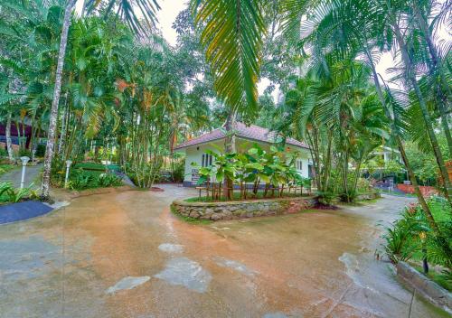a house with a lot of palm trees in front of it at Kedara Resort Wayanad by VOYE HOMES in Sultan Bathery