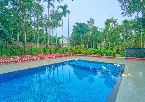 a swimming pool in a yard with trees at Kedara Resort Wayanad by VOYE HOMES in Sultan Bathery