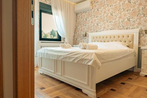 a bedroom with a bed with white sheets and a window at Casa Lumina in Gročanska Ada